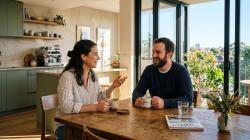 Couple having a relaxed conversation over coffee in a modern Australian apartment