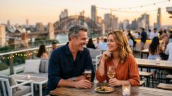 Hooking up after 40 in Australia Confident Australian couple in their late 40s sharing a relaxed evening at a stylish Sydney rooftop bar at golden hour